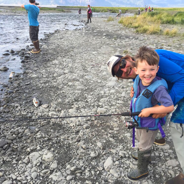 Father and Son Fishing While Smiling at Camera