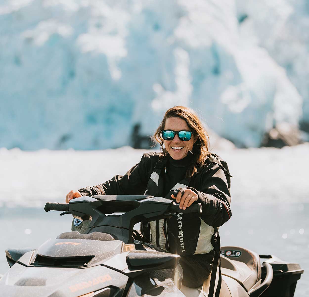 Young Man with Long Hair and Sunglasses Smiling while Riding Jetski