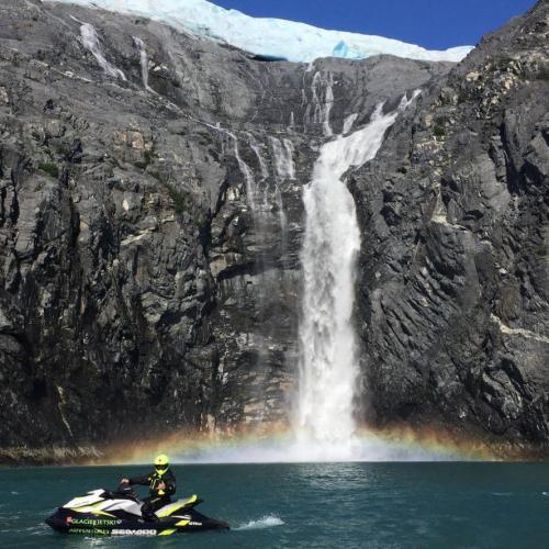 A waterfall makes a rainbow where it hits the ocean in Prince William Sound Alaska