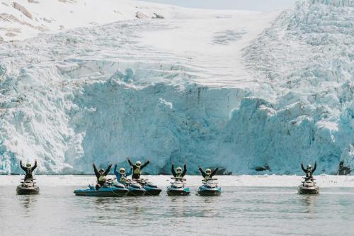 Jetski Riders Raising Hands and Posing for Photo in front of Large Glacier