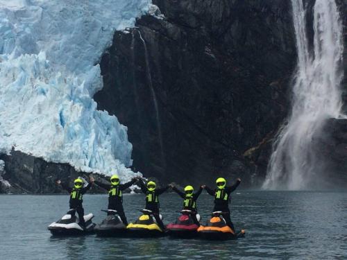 Jet skiers in front of a large glacier and waterfall