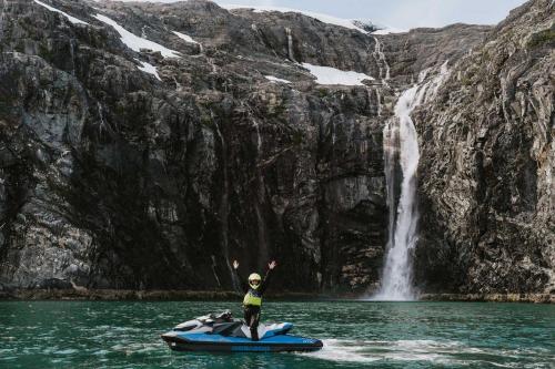 Jetski Rider Raising Hands in Celebration in front of Waterfall